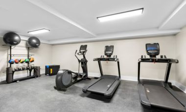 Fitness Room A clean and modern fitness center featuring treadmills, an exercise bike, and free weights for guests staying at Latitude Suites.