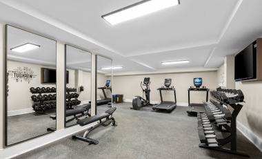A gym room featuring mirrors and various exercise equipment, located in a hotel near Capelli Sports Center.