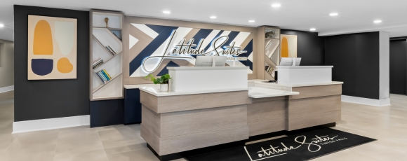 The hotel lobby features a large painting on the wall, enhancing the elegant atmosphere of Latitude Suites near Capelli Sports Center.