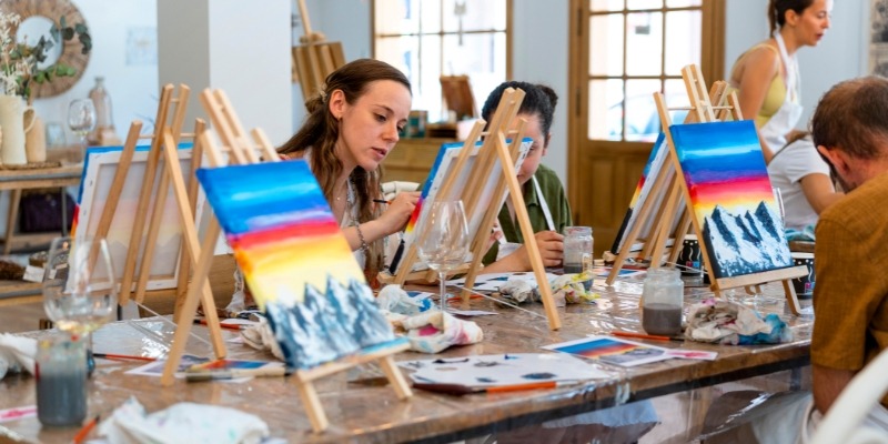 A group of people painting on easels in an art studio during an indoor arts activity at Jersey Shore.