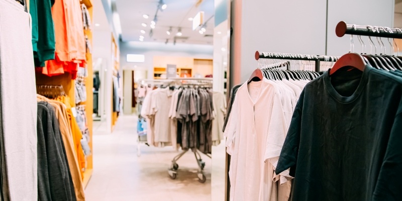 Clothes on hangers displayed in a clothing store, showcasing various styles for shoppers at Asbury Park Boardwalk.