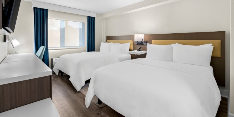 Hotel room with two beds and a television, perfect for families and groups enjoying indoor activities at Latitude Suites.