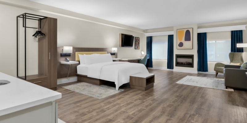A well-appointed hotel room with a bed, desk, and television, offering comfort and convenience at Latitude Suites, New Jersey.