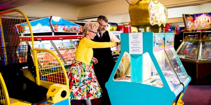 A couple enjoys playing games together at Silverball Retro Arcade in Jersey Shore, surrounded by colorful arcade machines.