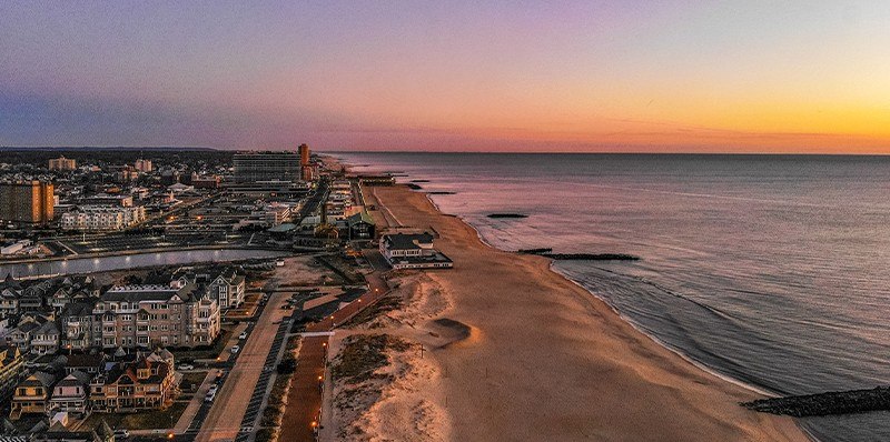 An aerial sunset view of the Jersey Shore coastline, showcasing nearby beaches and seaside attractions easily accessible from Latitude Suites.