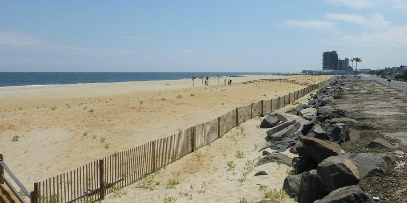 A beach scene at Sea Bright with sand dunes, a protective fence, and the ocean beyond.