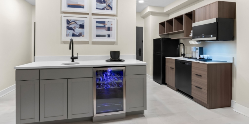 A modern kitchen featuring a refrigerator, microwave, and sink, showcasing luxury amenities at Latitude Suites.