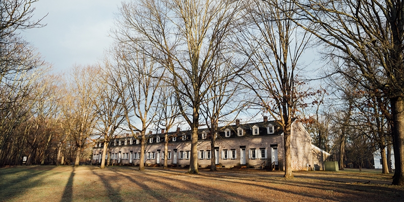 A spacious building with lush trees and grass in front, set in Allaire State Park, Jersey Shore, perfect for outdoor fun.