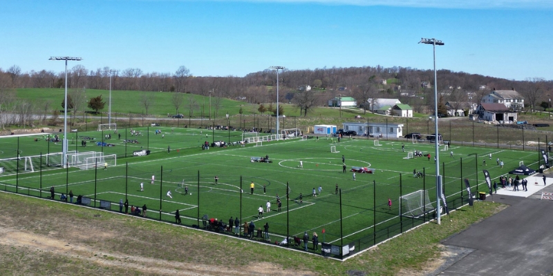 A vibrant soccer match taking place on a field at Capelli Sports Complex, Jersey Shore, with players and fans enjoying the game.