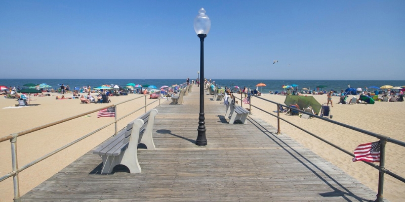 A scenic pier on the beach with benches and a light post, perfect for enjoying outdoor activities in Ocean Grove.