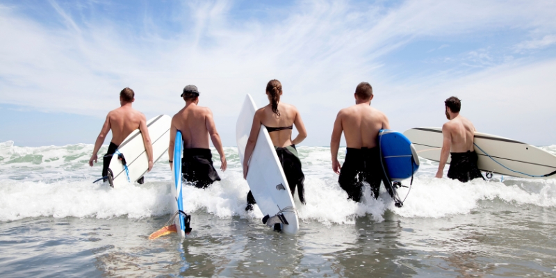 A group of people with surfboards standing in the ocean, enjoying outdoor activities at Jersey Shore.