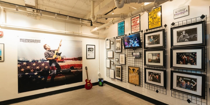 Interior view of a room adorned with framed pictures and posters, showcasing the Bruce Springsteen Center for American Music.