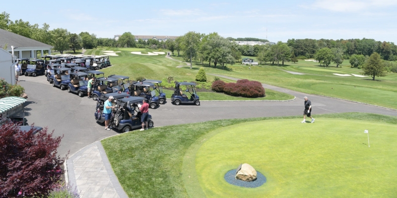Golf carts parked with players enjoying the green at the golf course in the Jumping Brook Country Club.