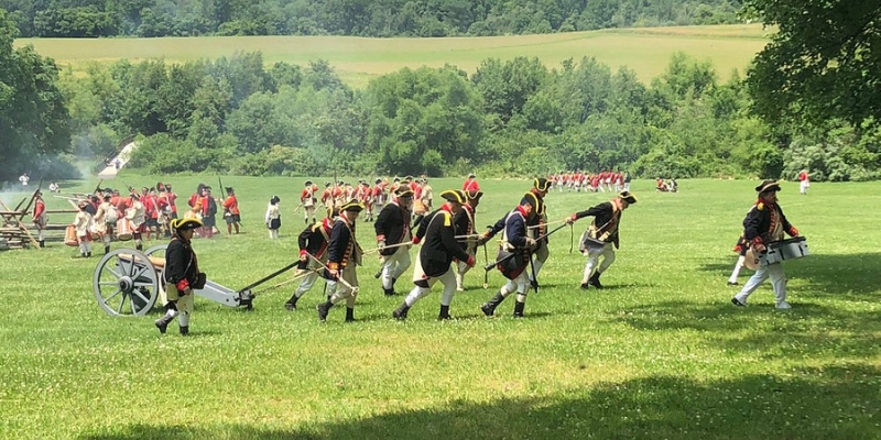 A group of men in period clothing marching across a field at Monmouth Battlefield State Park near Tinton Falls, NJ.