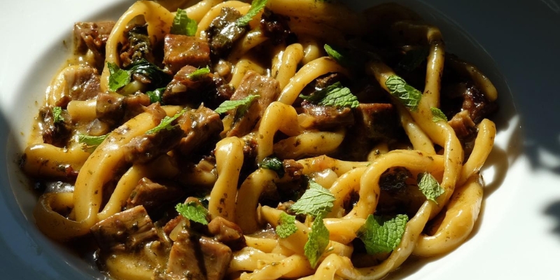 A white bowl filled with pasta, meat, and herbs, representing a dish from Nettie’s House of Spaghetti near Tinton Falls, NJ.
