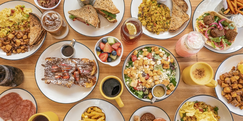 A table brimming with multiple plates of food, representing the dining experience at Toast, near in Tinton Falls, NJ.