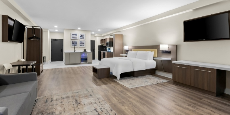 Contemporary hotel room showcasing a bed, desk, and television, part of Latitude Suites near Asbury Park's beaches.