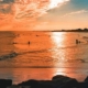 People enjoying a beach sunset in Cape May, New Jersey, with colorful skies and calm ocean waves.