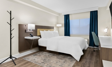 Hotel room featuring a bed, desk, and television, designed for quiet study near Monmouth University.
