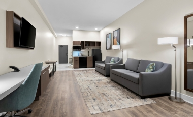 Hotel room featuring a couch, desk, and television, designed for student-friendly accommodations near Monmouth University.