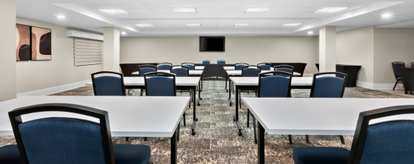 Conference room with tables and chairs, set for corporate meetings at a hotel near Seastreak to NYC.