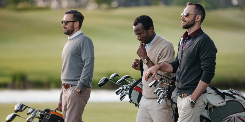 Three men stand together on a golf course, enjoying their time during a golf trip at Jersey Shore Golf Courses.