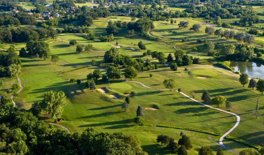 Aerial view of The Deal Golf & Country Club, showcasing lush greens, trees, and a water feature at the Jersey Shore.