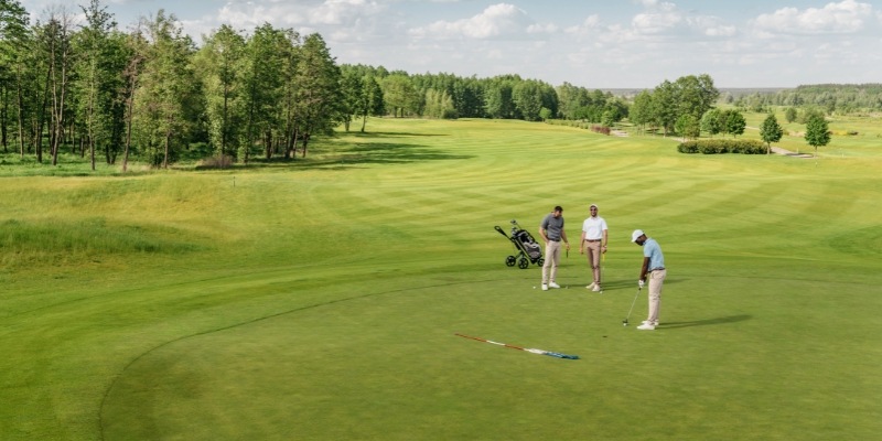 Three people engaged in a round of golf on a scenic green course at Jersey Shore Golf Courses.