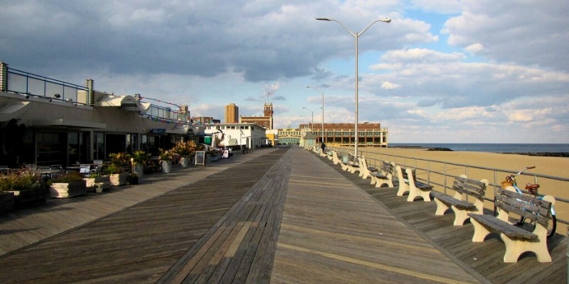 A scenic boardwalk with benches and tables, inviting visitors to enjoy outdoor activities at Asbury Park Beach.