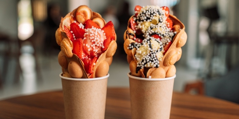 Two paper cups filled with waffle ice cream on a table, showcasing a delicious treat at Coney Waffle Ice Cream near Monmouth University.
