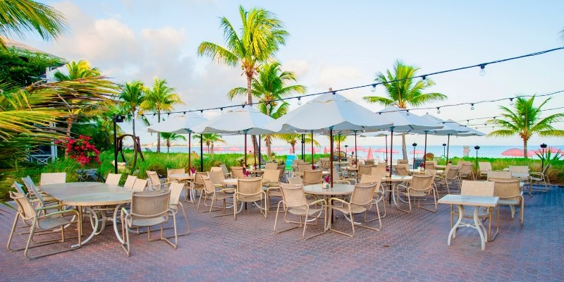 Scenic outdoor dining at the beach, highlighting tables and chairs at Rooney’s Oceanfront Restaurant with ocean backdrop.