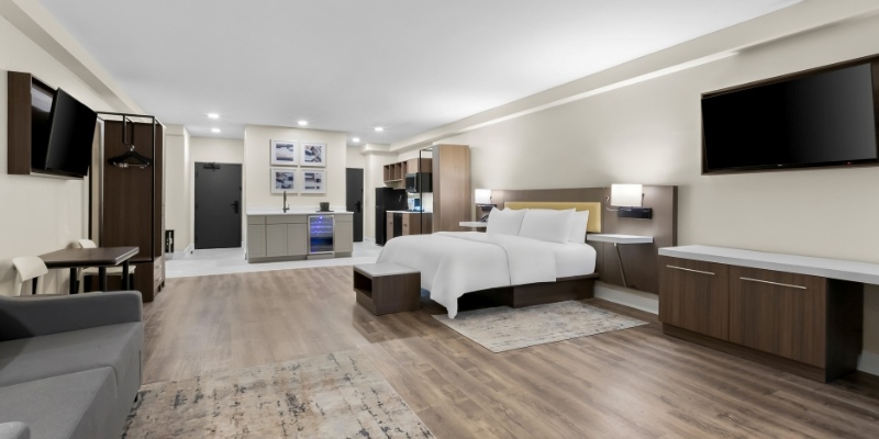 A hotel room design showcasing a bed, desk, and TV, part of the Latitude Suites for families visiting the Jersey Shore.