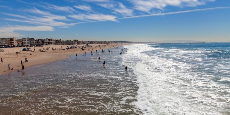 A vibrant Jersey Shore beach scene featuring people walking along the shore and waves rolling in on a sunny day.