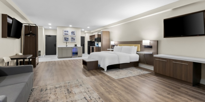 Contemporary hotel room with a bed, desk, and television, representing the inviting atmosphere of Latitude Suites.