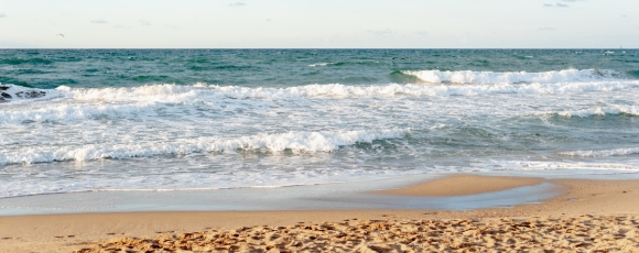 A sandy beach with gentle waves and a small body of water, near Keansburg Amusement Park at the Jersey Shore.
