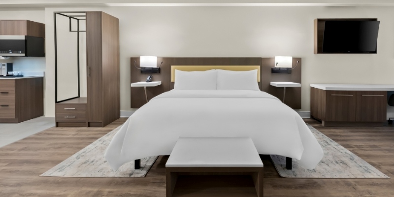 Stylish hotel room showcasing a bed, desk, and kitchen, encouraging summer stays at Latitude Suites on the Jersey Shore.