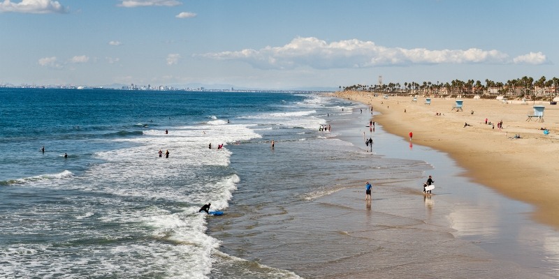 People enjoying a sunny day at the beach, with umbrellas and towels scattered along the Jersey Shore.