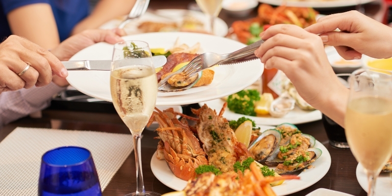 A group of people enjoying seafood and champagne at a restaurant, featured in the Jersey Shore Travel Guide.