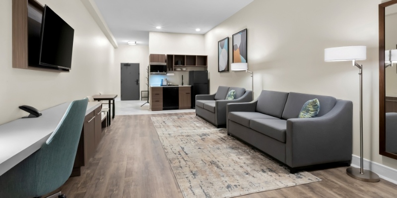 Stylish hotel room showcasing a couch, television, and kitchen, as featured in Latitude Suites perfect for stay during the Jersey Shore tour.