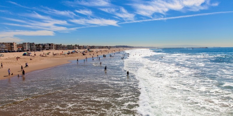 People enjoy a day at the beach on the North Jersey Shore, walking on the sand as waves roll in nearby.