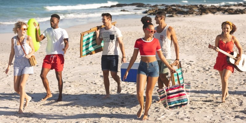 A lively group of young people walks on the beach, highlighting summer activities in New Jersey.
