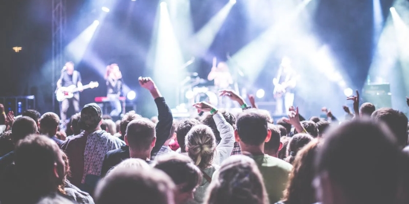 A lively crowd at an Asbury Park concert, with attendees raising their hands in excitement.