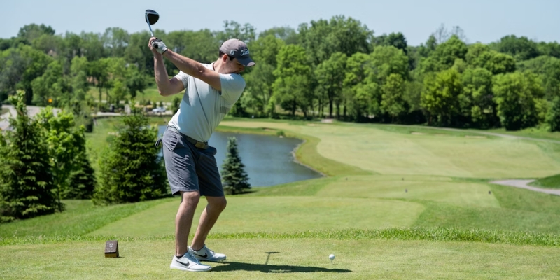 A man is about to hit a golf ball on a well-maintained course, representing summer golfing options in New Jersey.