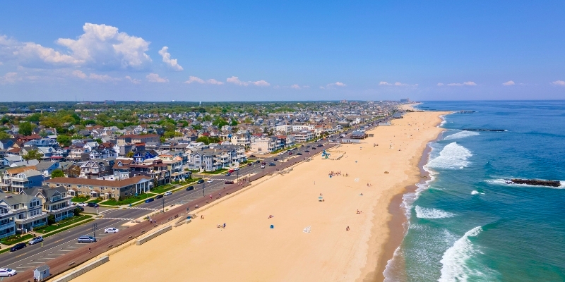 Aerial view of a beach town in Long Branch, New Jersey, showcasing sandy beaches and nearby houses under a clear sky.