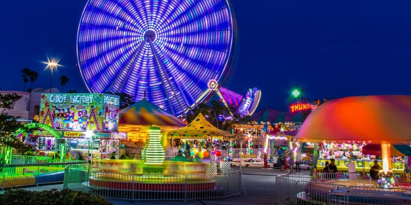 A vibrant carnival at night featuring a lit ferris wheel and various rides, showcasing the Monmouth County Fair in New Jersey.