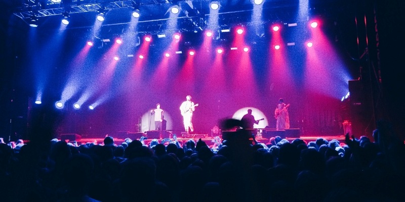 A vibrant concert scene at PNC Bank Arts Center, featuring an engaged audience and dazzling bright lights.