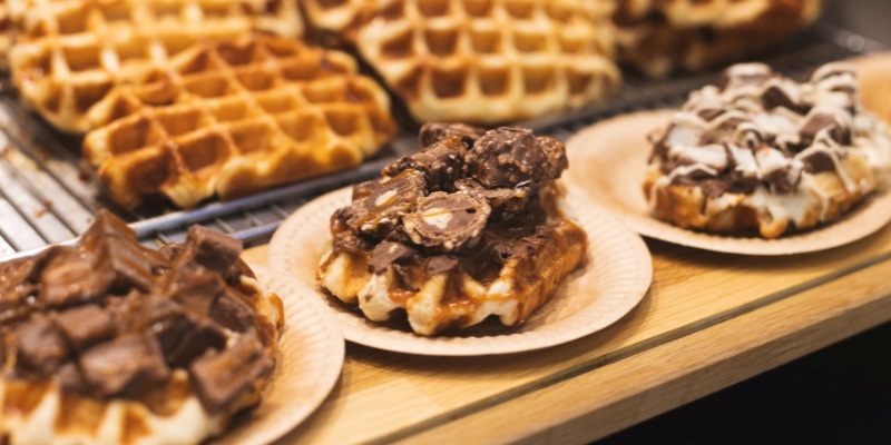 A series of waffles lined up on a wooden table, highlighting a tempting culinary treat in a casual setting.