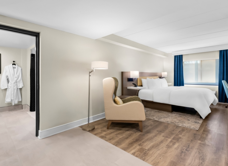 Comfortable hotel room showcasing a bed, chair, and television, near the Stone Pony venue.