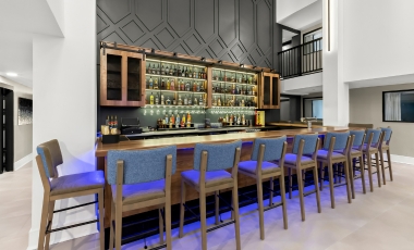 A stylish bar with blue lighting and bar stools, located at the Hotel Near Stone Pony's onsite bistro and bar.