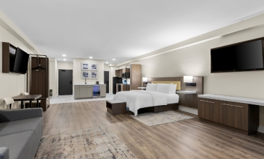 Contemporary hotel room showcasing a bed, desk, and television, offering luxury accommodations near Stone Pony.